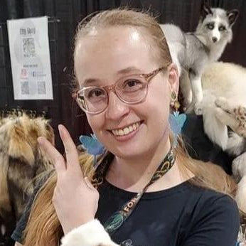 Person with glasses and a fox on their shoulder in an indoor setting
